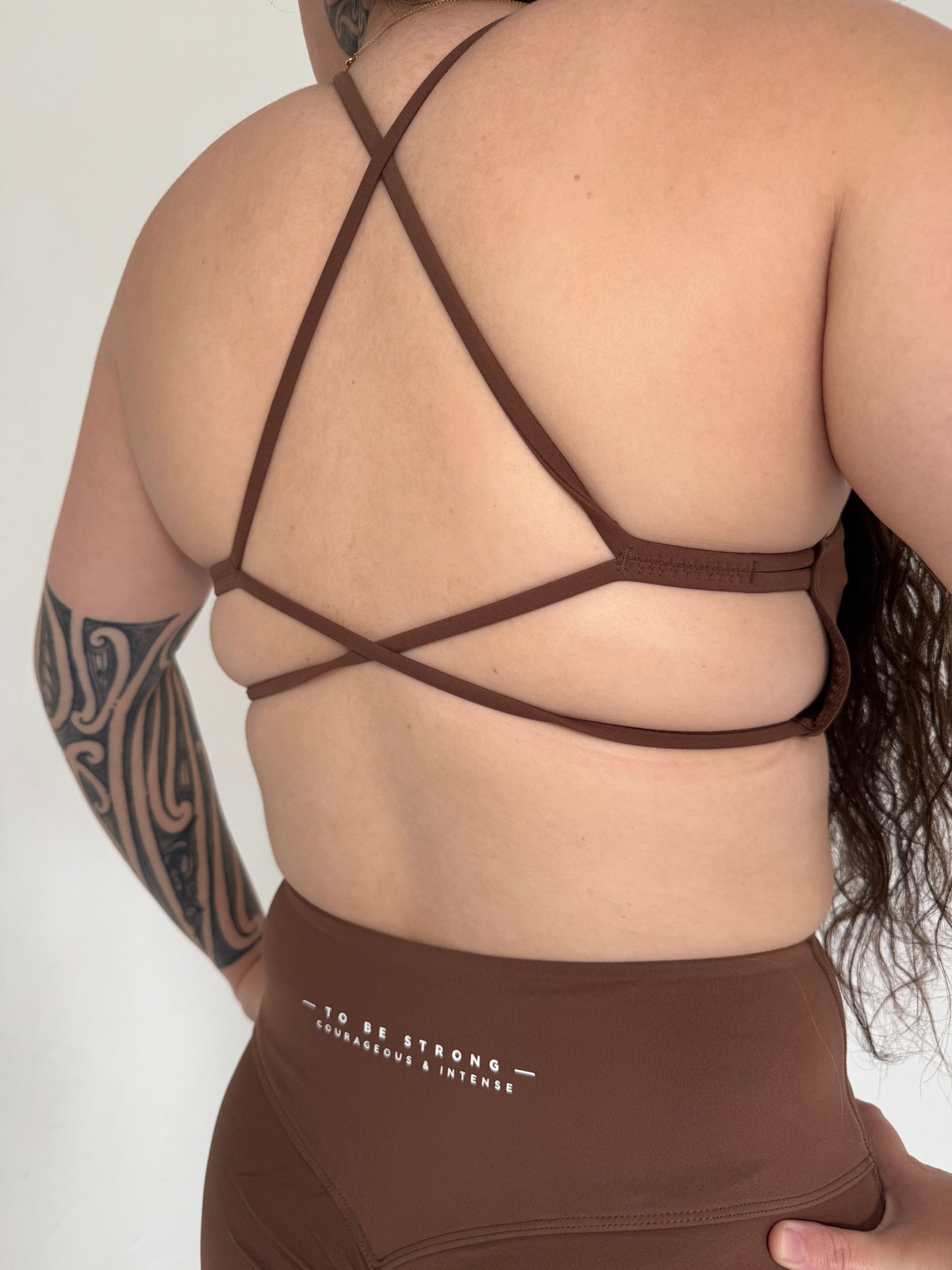 KAHA brown sports bra with criss-cross back straps and matching high-waisted flare leggings with To Be Strong text