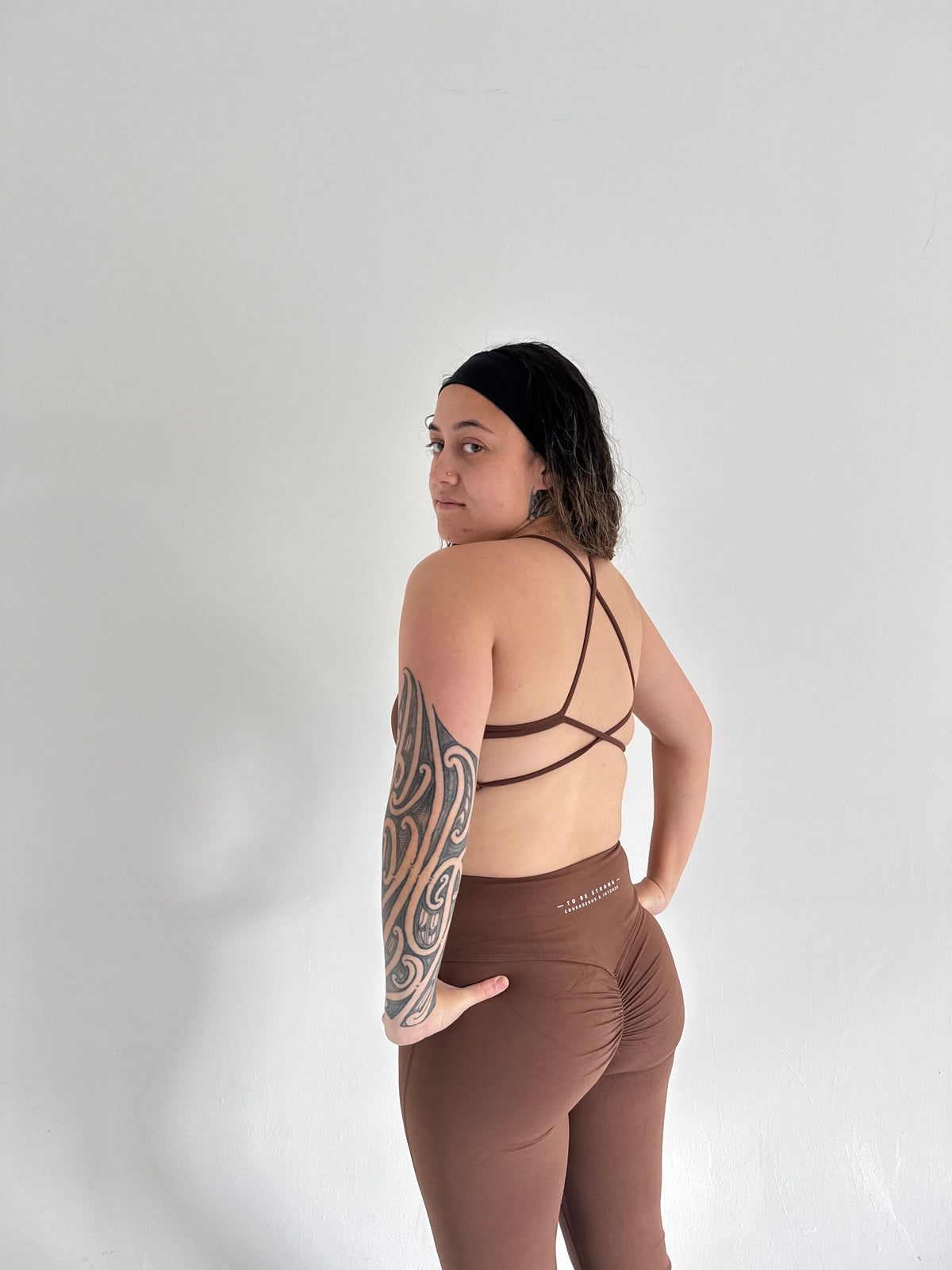 KAHA brown matching sports bra with criss-cross back and high-waisted flare leggings with back ruching detail
