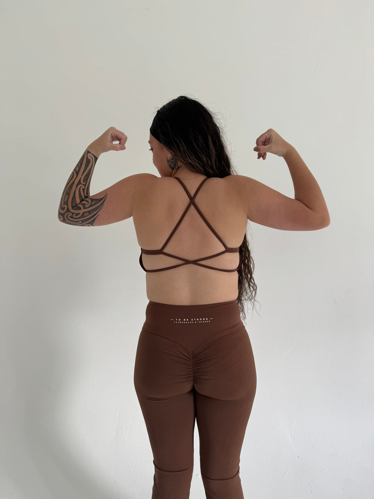 KAHA brown matching sports bra with criss-cross back and high-waisted flare leggings with back ruching detail