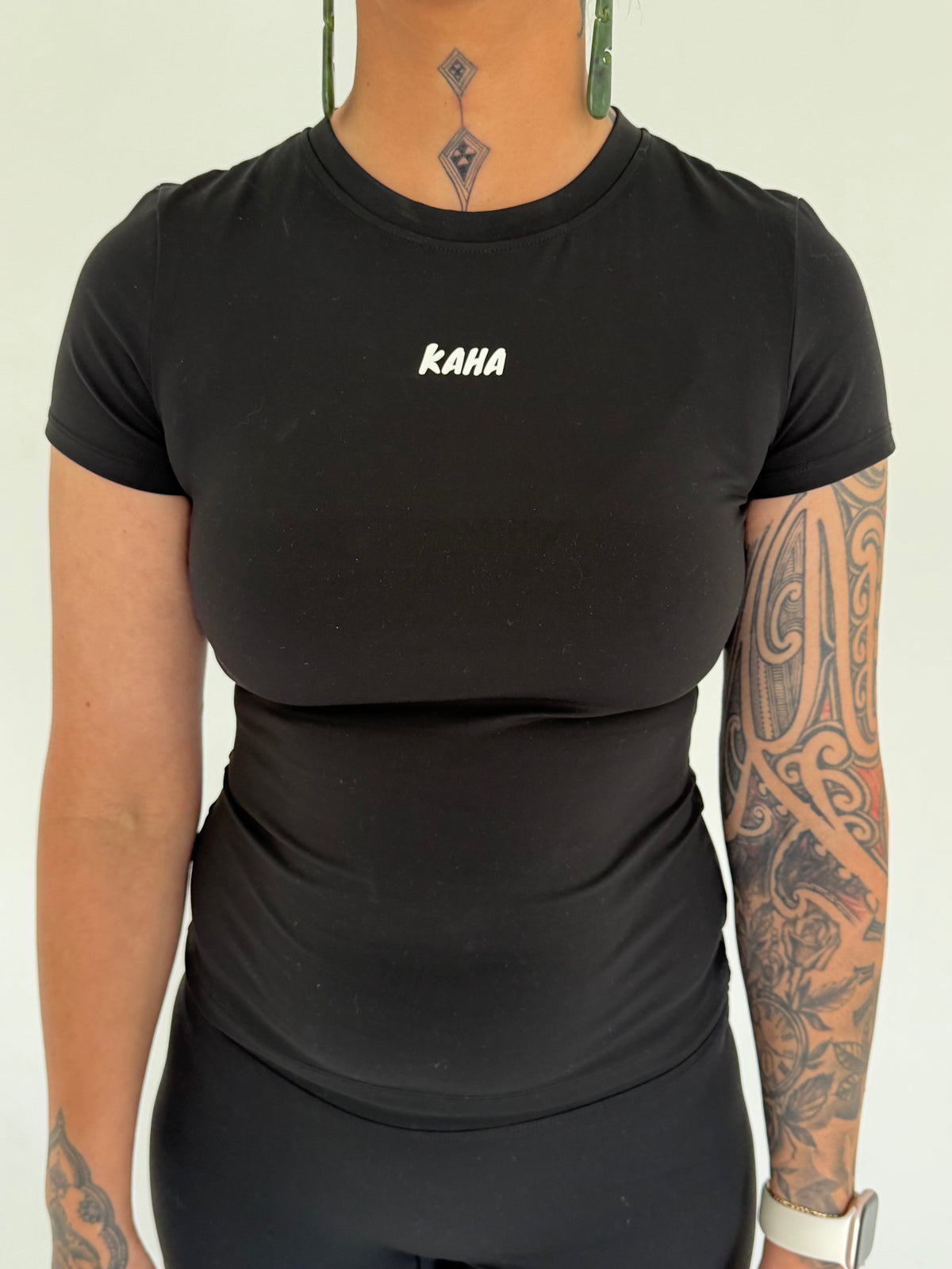 KAHA fitted black short sleeve performance t-shirt with crew neckline and white chest logo on a tattooed model