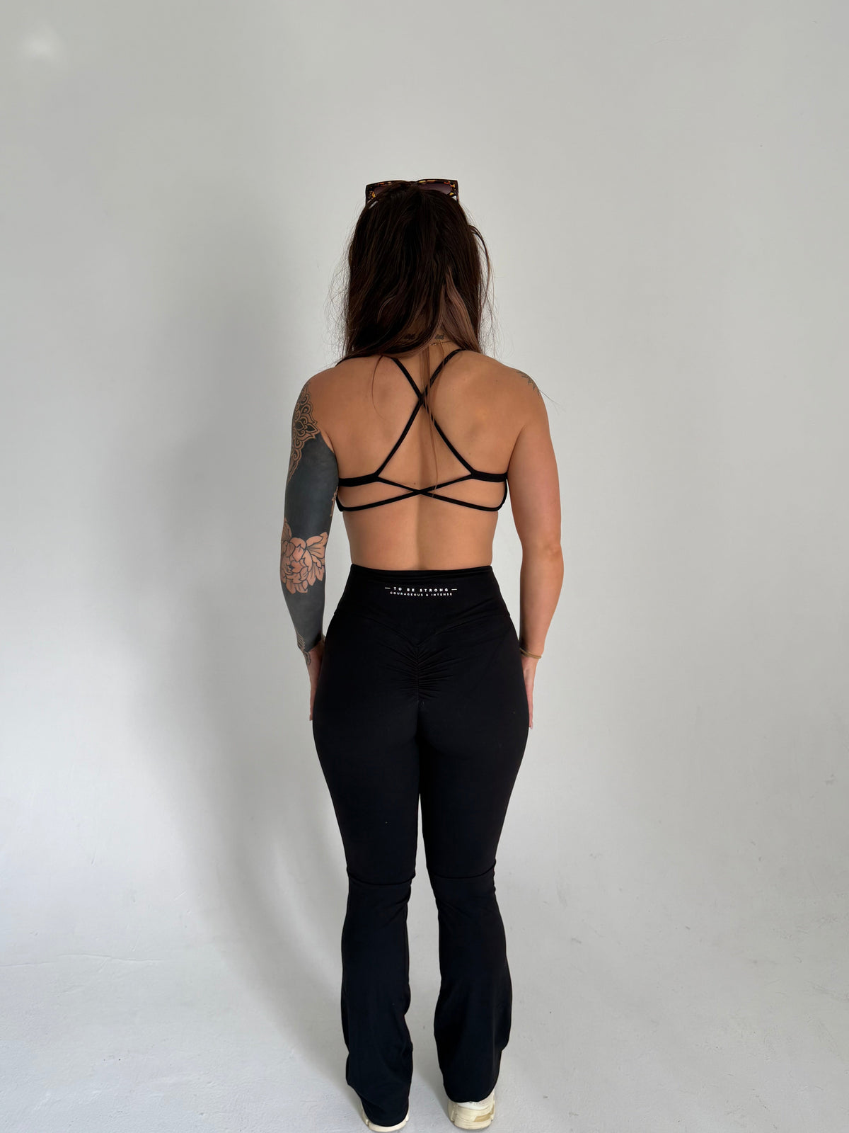 KAHA black matching set featuring a strappy back sports bra and high-waisted flared leggings on a woman from behind.