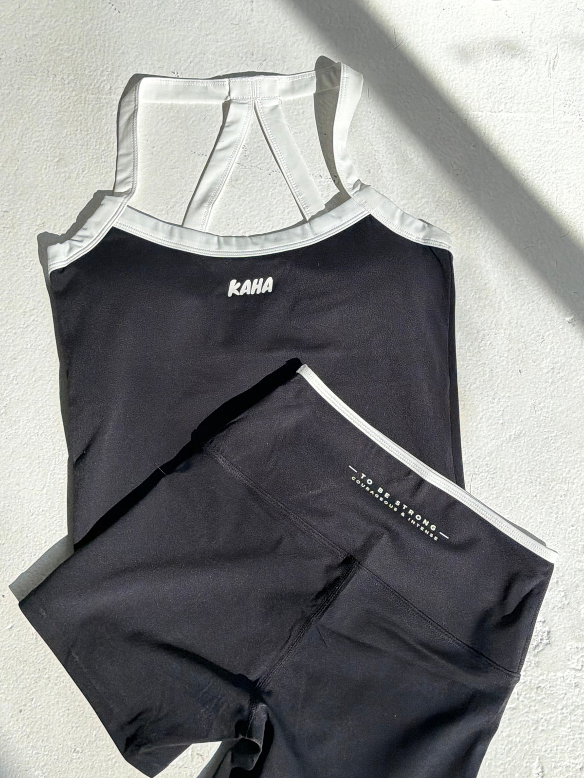 KAHA Onyx Set featuring a black halter sports bra and high-waisted shorts with white contrast trim and logo details.