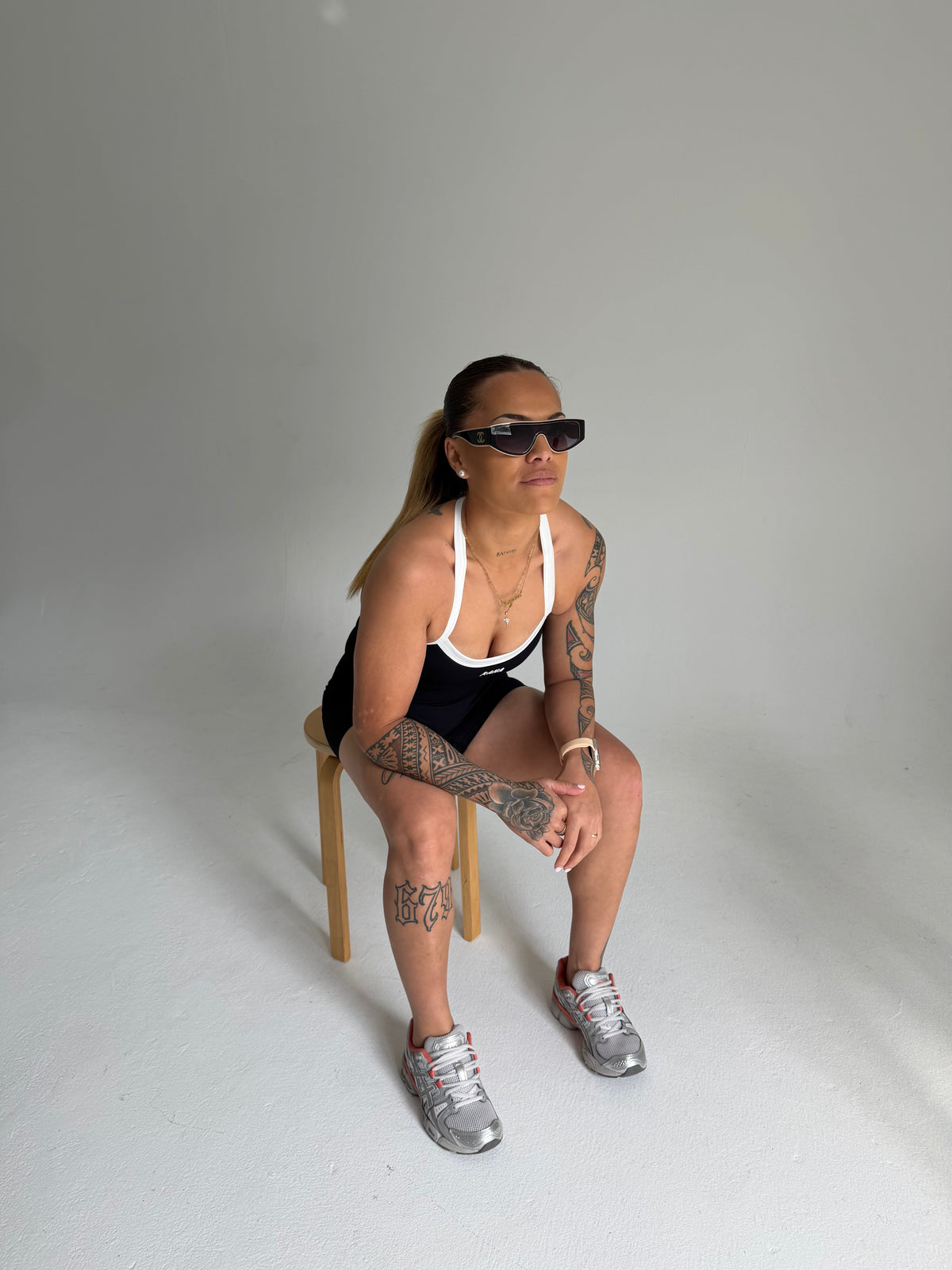 KAHA Onyx Set featuring a black halter sports bra with white trim and matching shorts worn by a model on a stool.