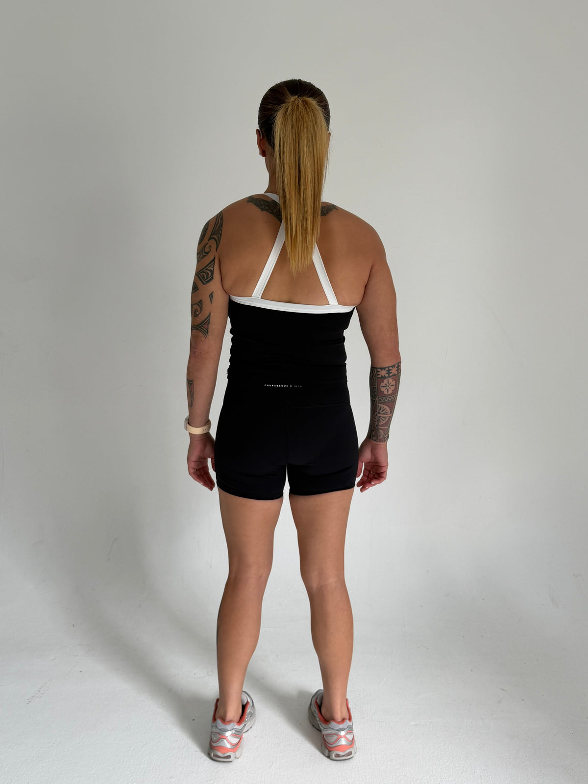 KAHA Onyx Set featuring a black halter-style sports bra with white straps and high-waisted shorts on a model